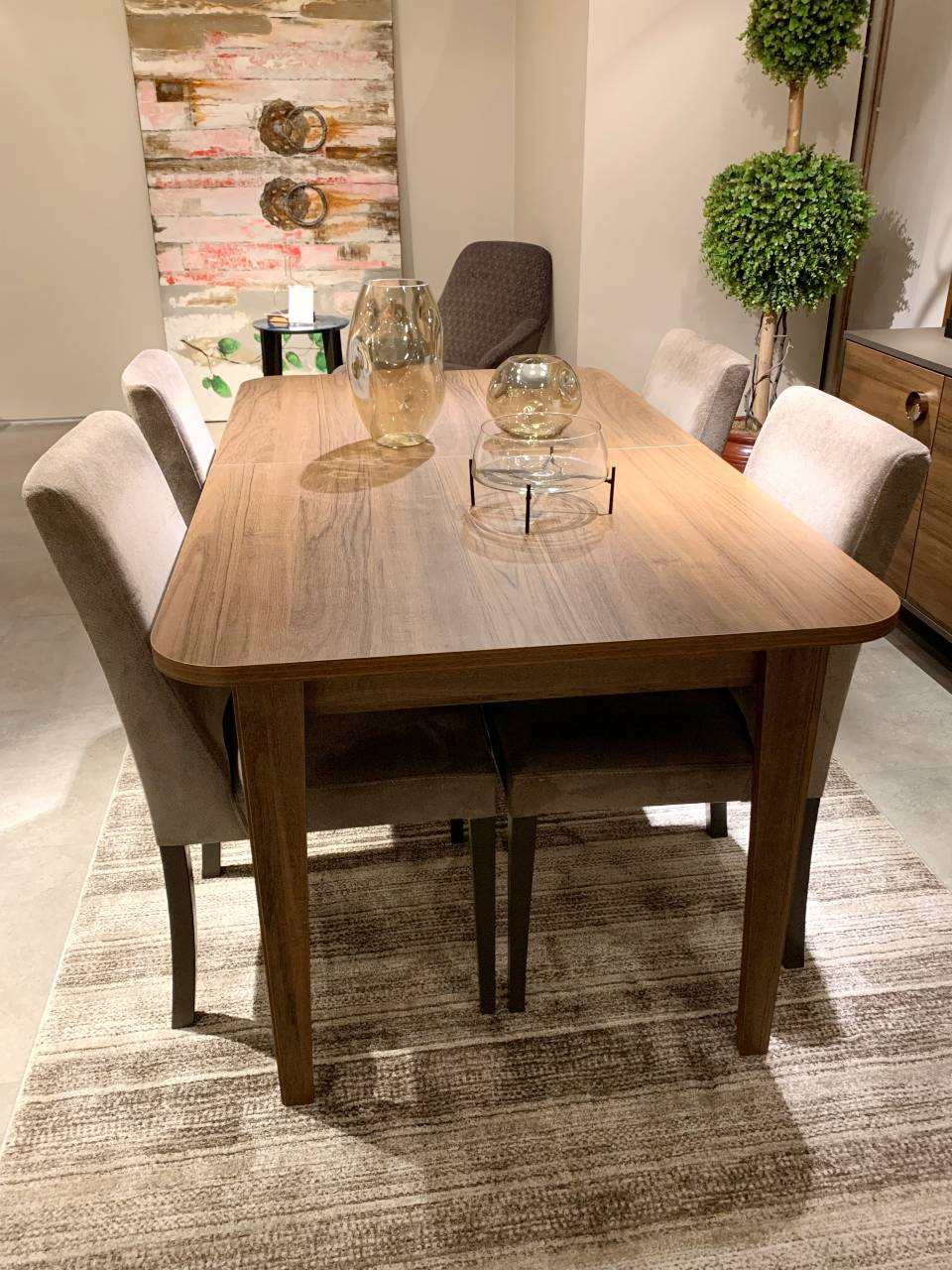 brown wooden dining table with round corners and four velvet beige chairs