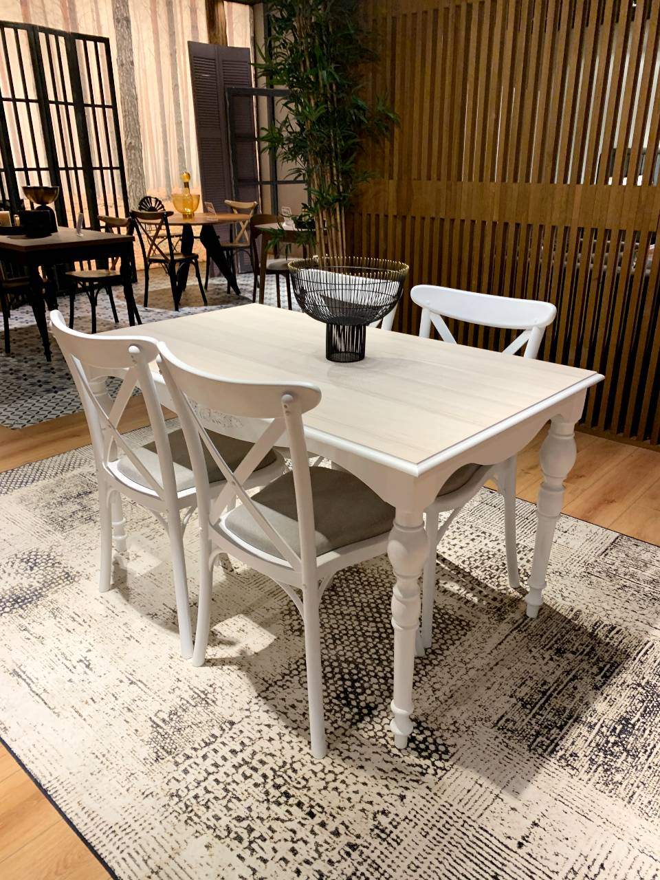 big white dining table with four white chairs